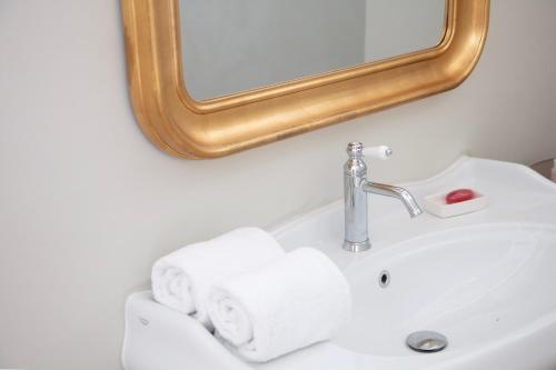 a bathroom sink with a mirror and towels at La Bâtisse en Blanc in Golfe-Juan