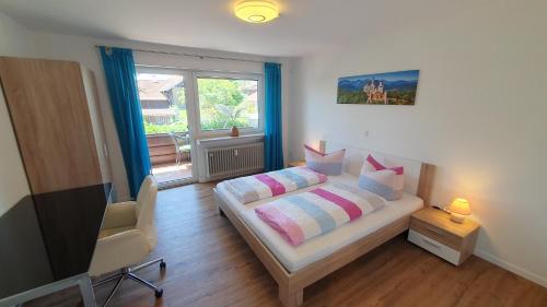 sypialnia z łóżkiem, telewizorem i oknem w obiekcie Ferienwohnung Melinda w Füssen