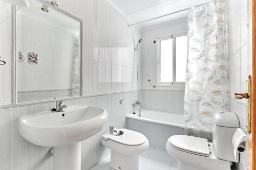 uma casa de banho branca com um lavatório e um WC em Palacio Del Mar em Torrevieja