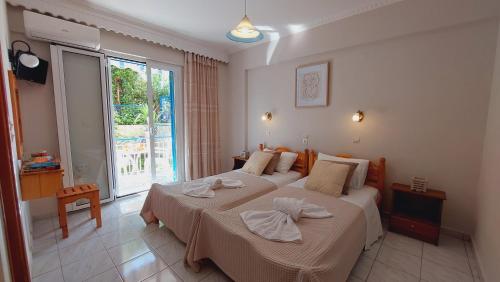 a bedroom with two beds and a large window at Emilios Eleni studios in Nydri