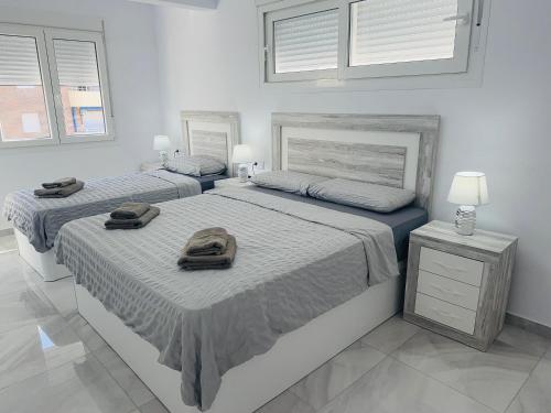 two beds in a white bedroom with towels on them at Luxury Private New 2023 Villa Mirelle in Torrevieja