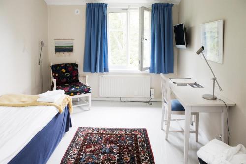 a bedroom with a bed and a desk and a chair at Skeviks Gård in Gustavsberg