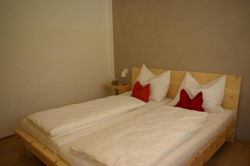 a white bed with red pillows on it at ZeiTraum Ferienwohnung Tafelbühl in Elzach