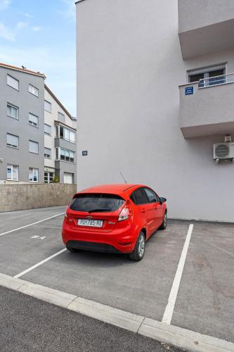 a red car parked in a parking lot next to a building at Apartment Leone Medulin in Medulin