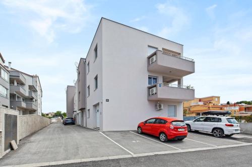 a white building with two cars parked in a parking lot at Apartment Leone Medulin in Medulin