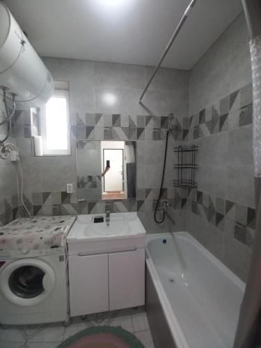 een badkamer met een wasmachine, een wastafel en een bad bij Guest house B&B in Kochkorka
