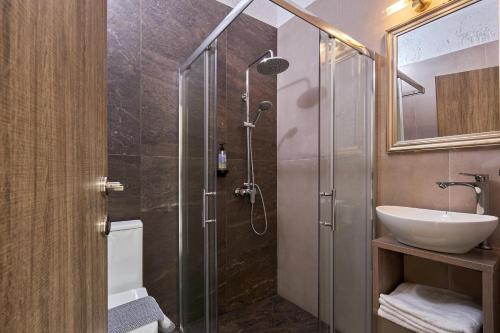 a bathroom with a glass shower with a sink at Charm Hotel, Hersonissos in Hersonissos