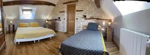 1 dormitorio con 2 camas y pared de piedra en Le panorama des Hautes-Côtes, en Fussey