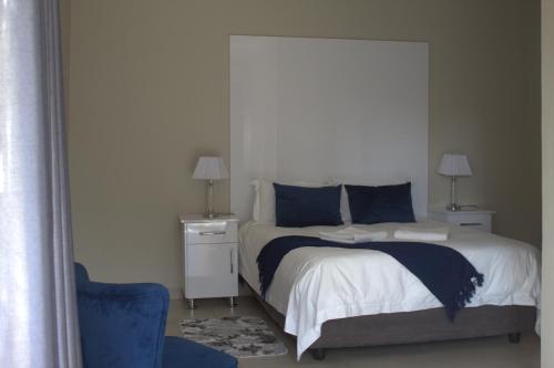a bedroom with a bed and a blue chair at Kanyane @ Graskop in Graskop