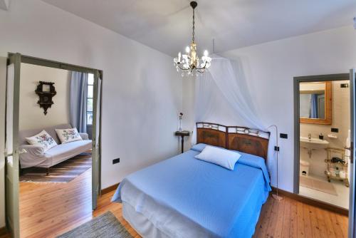 a bedroom with a blue bed and a chandelier at La Rosa al Roseto del Drago in San Bernardo