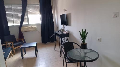 a living room with a table and a tv in a room at דירת אירוח בית שיאים in Beer Sheva