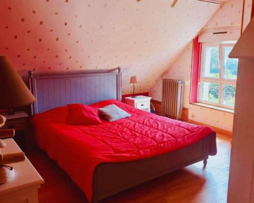 a bedroom with a red bed with a red comforter at Maison en pierre au milieu du bocage in Coulouvray-Boisbenâtre