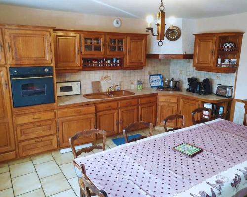 une cuisine avec des placards en bois et une table avec un chiffon de table blanc dans l'établissement Maison en pierre au milieu du bocage, à Coulouvray-Boisbenâtre