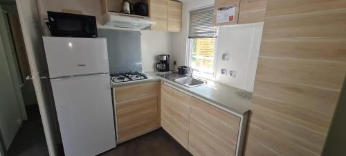 uma pequena cozinha com um frigorífico e um lavatório em Joli Mobil Home em Agde