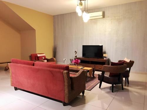 a living room with a red couch and chairs and a television at Malacca City Center Town House by 360HOME in Melaka