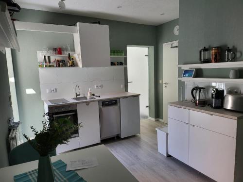 uma cozinha com armários brancos, um lavatório e um fogão em Exquisite, gemütliche kleine Wohnung mit Balkon em Wolmirstedt