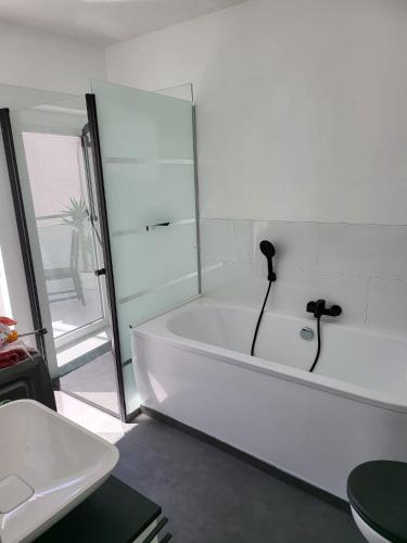 biała łazienka z wanną i umywalką w obiekcie Exquisite, gemütliche kleine Wohnung mit Balkon w mieście Wolmirstedt