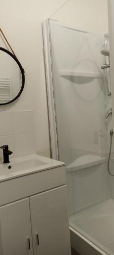 een witte badkamer met een douche en een wastafel bij Sous l'arbre aux papillons 