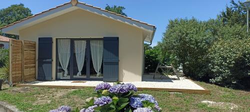 een klein huis met blauwe deuren en paarse bloemen bij Sous l'arbre aux papillons 