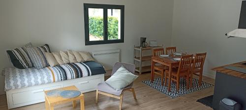 een woonkamer met een bed en een tafel en stoelen bij Sous l'arbre aux papillons 