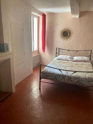 a bedroom with a bed and a window and a red curtain at Maison a Rustrel (A coté du Colorado Provençal ) in Rustrel