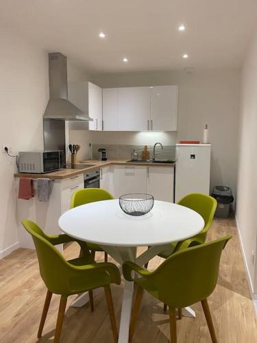 une cuisine avec une table blanche et des chaises vertes dans l'établissement LESLIELOU T2, à La Ciotat