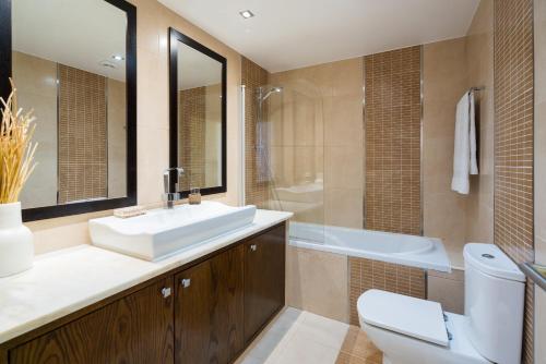 a bathroom with a sink and a toilet and a tub at Marina de Lagos Penthouse - 250m from beach in Lagos