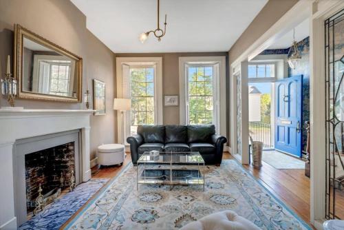 a living room with a black couch and a fireplace at Historic Petersburg Row Home in Petersburg