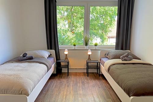 two beds in a room with a window at Work & Stay Apartment with Balcony in Osnabrück