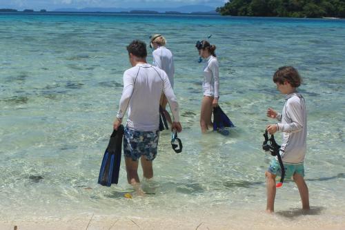 a group of people standing in the water on the beach at Leleana Resort Kolombangara in Kolombangara Island