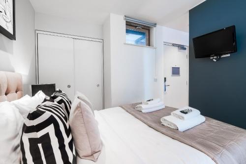 a bedroom with a bed with a tv on the wall at Artillery Lane in London