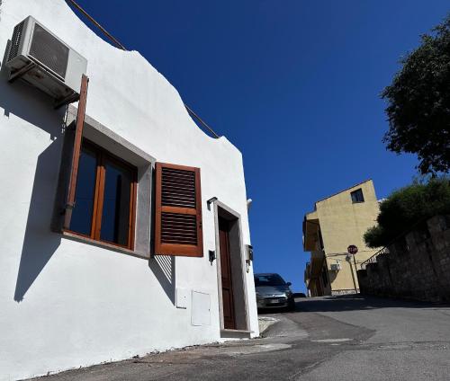 - un bâtiment blanc avec une fenêtre et une voiture dans l'établissement La Piccola Perla, à Gonnesa