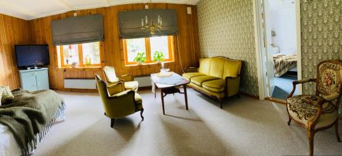 Tretten的住宿－Glomstad Gjestehus，客厅配有沙发、椅子和桌子