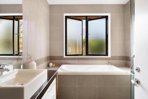 a bathroom with a tub and a sink and two windows at Skye Scape - Jacks Point Retreat in Queenstown