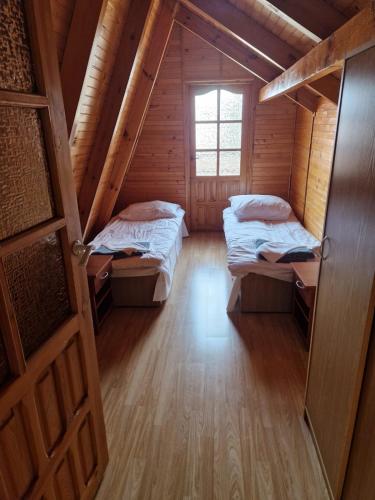 an attic room with two beds and a window at Domki MEDYK in Jantar