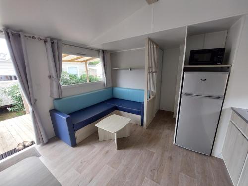 a small kitchen with a blue couch and a refrigerator at Mobil Home (Clim, TV)- Camping Falaise Narbonne-Plage 4* - 003 in Narbonne-Plage