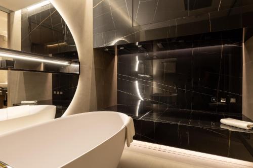 a bathroom with a tub and a black tile wall at Wellington Hotel & Spa Madrid in Madrid