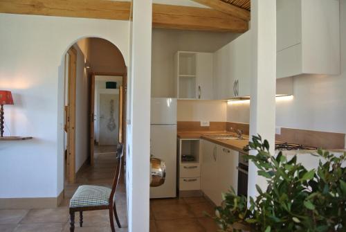 cocina con armarios blancos, mesa y silla en Auberge Santu Martine: Cottage with pool (Pira), en Galtellì