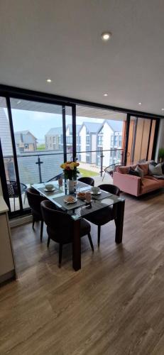 a living room with a table and chairs and a large window at Stunning Sea View Two Bed Two Bathroom Apartment in Porthcawl