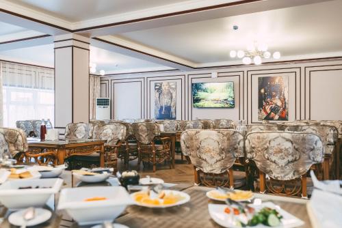 a dining room with tables and chairs and paintings on the walls at Dostyk Kokshetau in Kokshetau