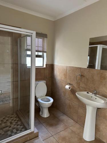 a bathroom with a toilet and a sink and a shower at El Dorado 78 in Oudtshoorn