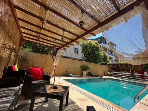 a swimming pool with a wooden pergola and a table and a swimming pool at Beyaz Melek Hotel in Antalya
