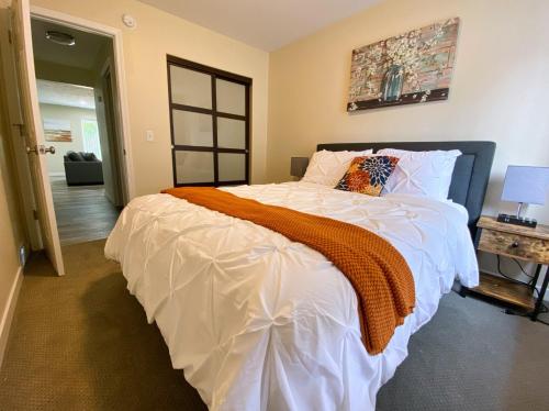 a bedroom with a large white bed with an orange blanket at 2 BR Family Friendly Nature Getaway near Golf Course in Kalamazoo