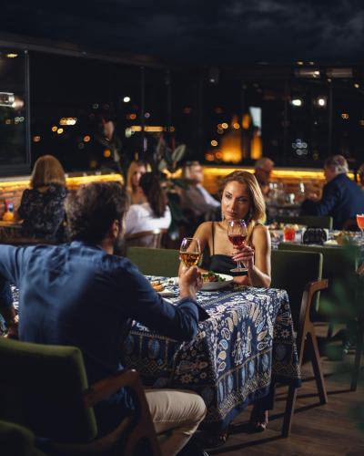a man and woman sitting at a table with wine glasses at TbiliSee Hotel in Tbilisi City