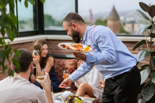 a man is holding a plate of food at TbiliSee Hotel in Tbilisi City
