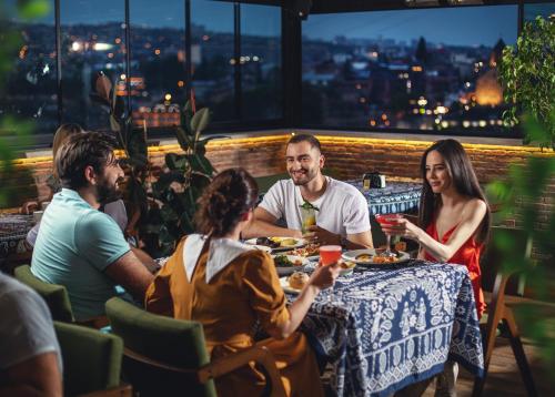 a group of people sitting around a table in a restaurant at TbiliSee Hotel in Tbilisi City