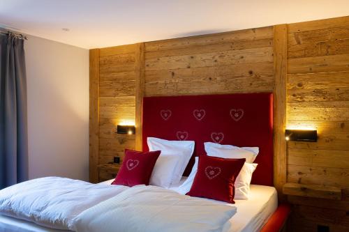 a bed with a red headboard and red pillows at Eden du Boenlesgrab in Lautenbach