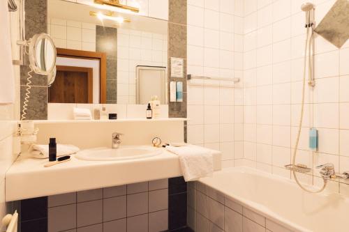 a white bathroom with a sink and a tub at Hotel Jägerhof in Zams