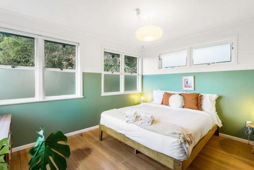 a bedroom with a bed with green walls and windows at Hollys Abode with Piano and Deck in Auckland