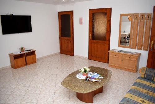 een woonkamer met een tafel en een televisie bij Nóra apartman in Harkány